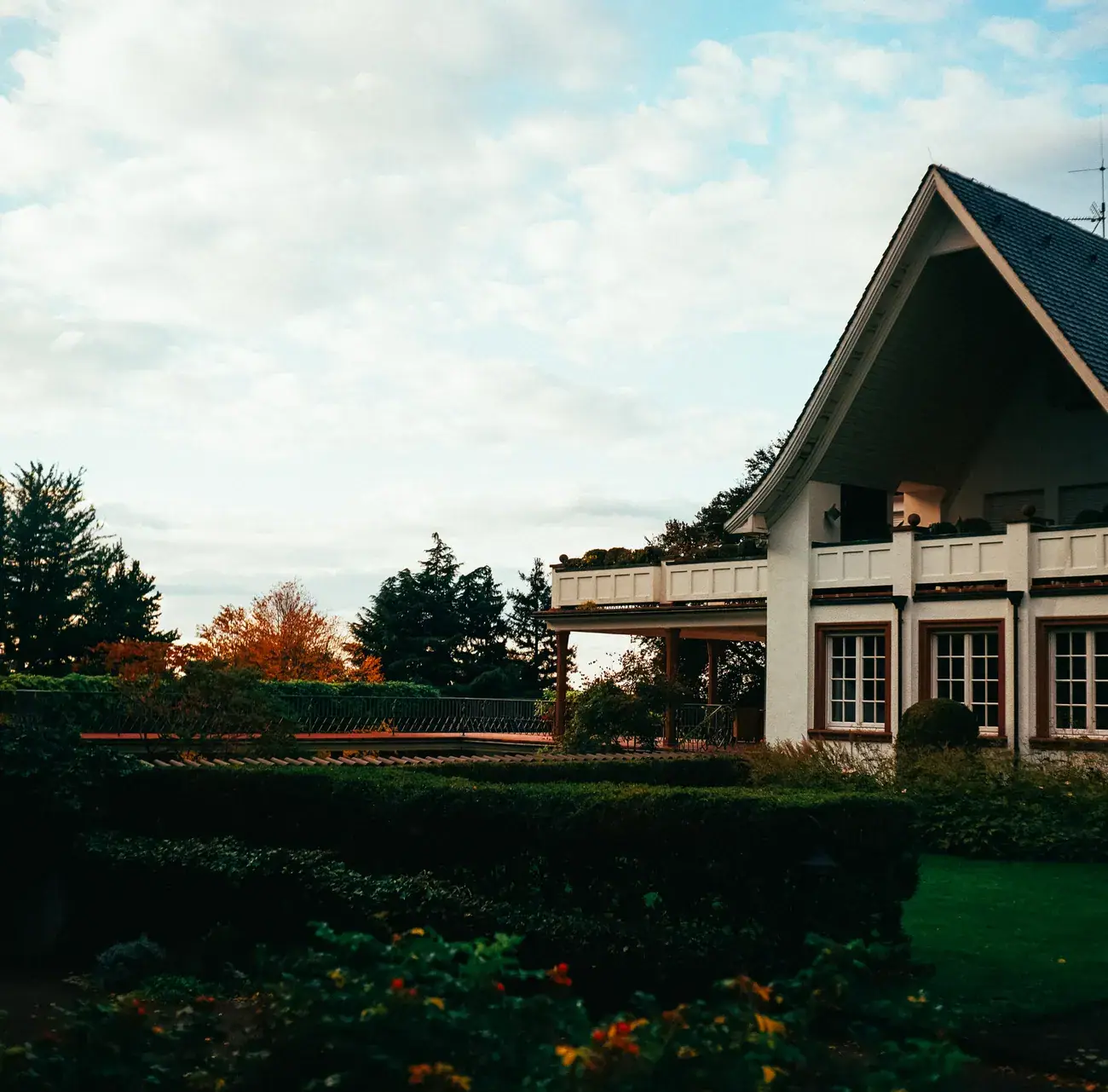 House with a covered porch and railings under an autumn sky