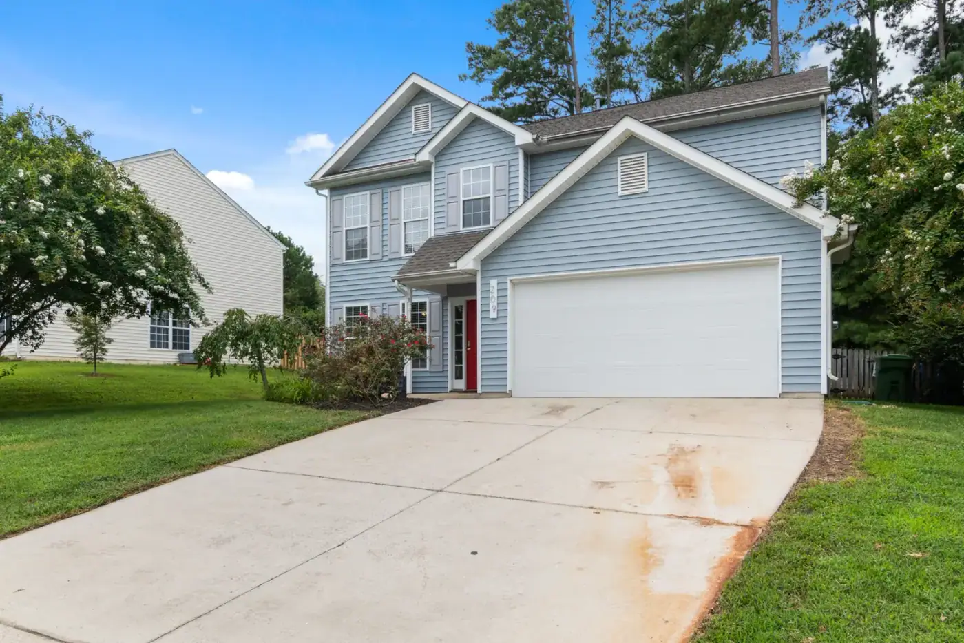 Two-storey house with pale blue vinyl siding and a wide concrete driveway