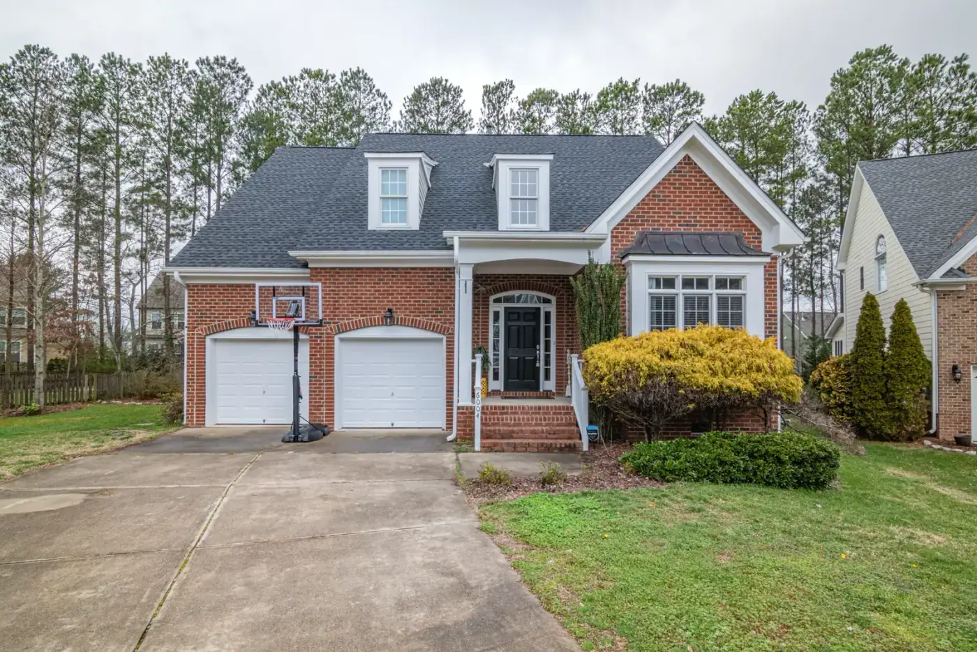 Brick home with two garage doors and a wide concrete driveway